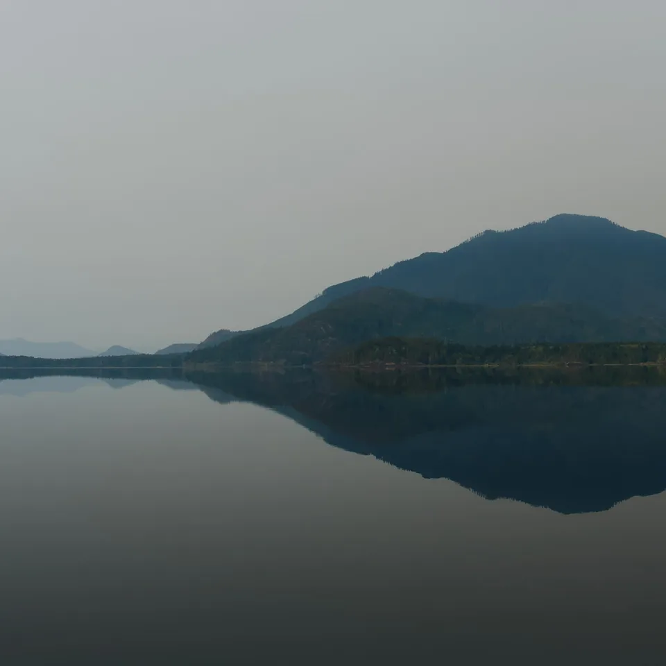 Mountains and shore reflected in a still lake (panel 2 of 4)