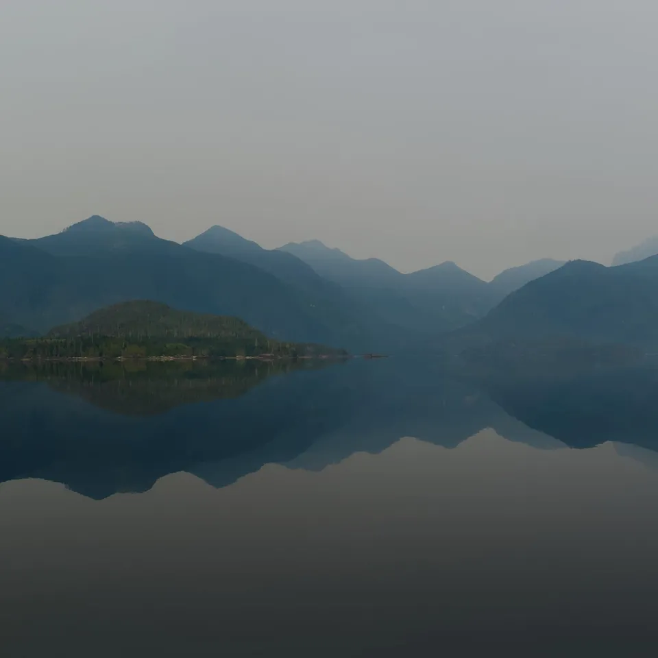 Mountains and shore reflected in a still lake (panel 3 of 4)