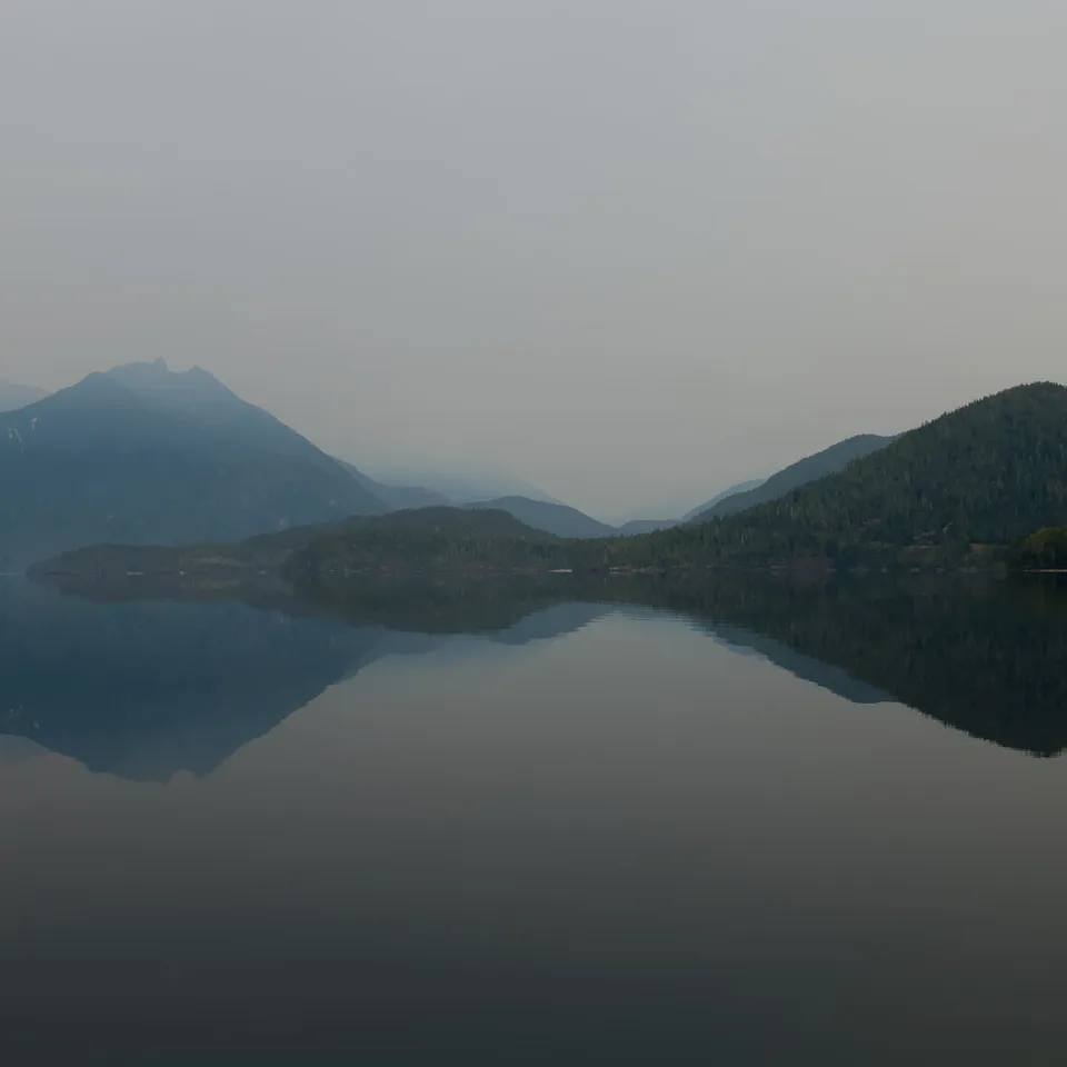 Mountains and shore reflected in a still lake (panel 4 of 4)