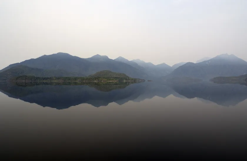 A mirror-like lake reflecting a far shorline
