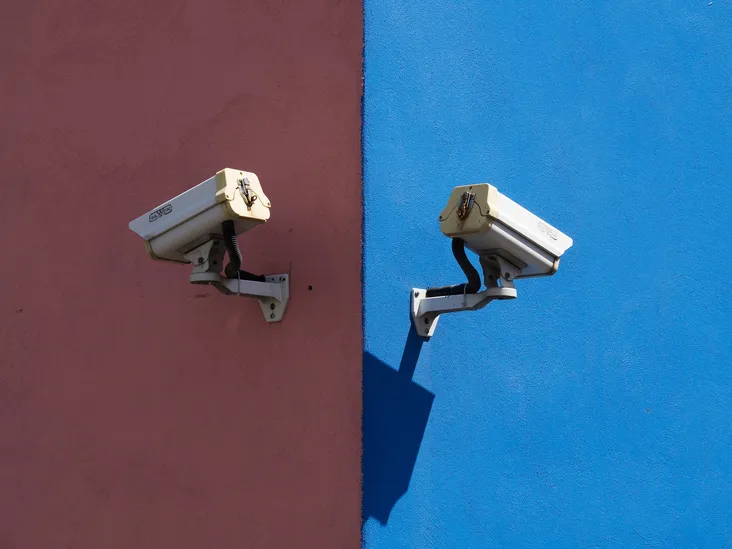 Security cameras against contrasting pink and blue walls