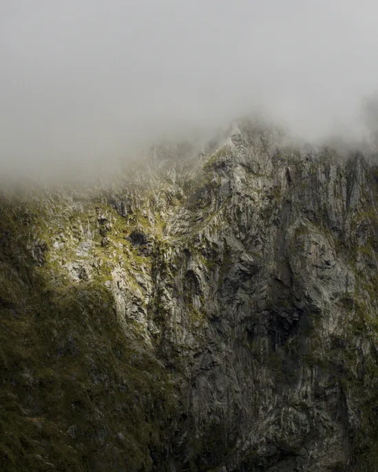 A rocky cliff face on a foggy morning