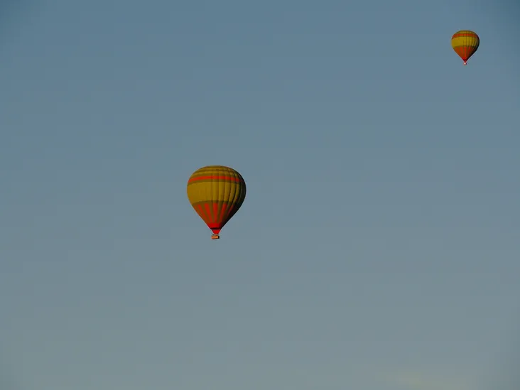 Two hot air balloons hovering high in the morning sky